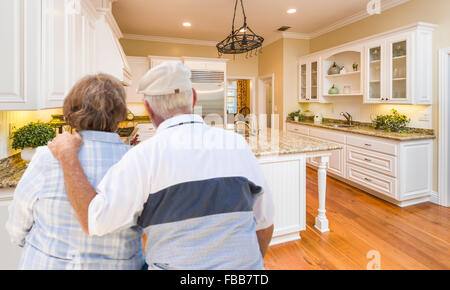 Happy Senior Couple Looking Over Beautiful Custom Kitchen Design. Stock Photo