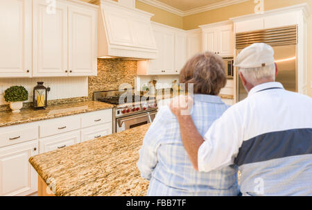 Happy Senior Couple Looking Over Beautiful Custom Kitchen Design. Stock Photo