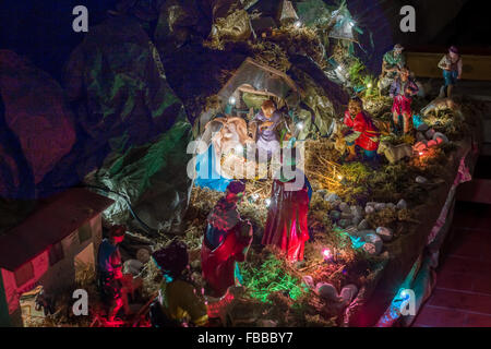 Statues in a Christmas Nativity scene, the Blessed Virgin Mary and Saint Joseph watch over the Holy Child Jesus in a manger in the straw as the ox and the donkey are warming while the three wise men bring gifts of gold, frankincense and myrrh Stock Photo