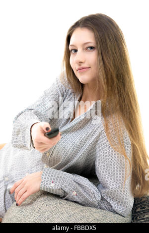 Beautiful young girl lying comfortable, pressing button on remote control, switching channels on tv, watching television Stock Photo