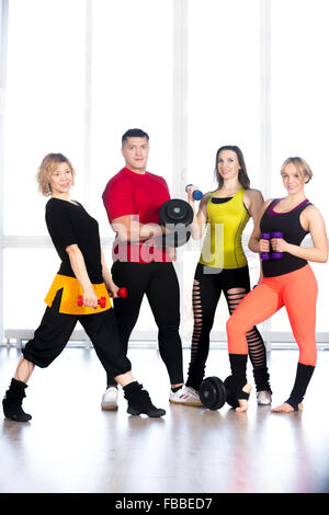 Group of four sporty people holding dumbbells of different sizes, doing weightlifting, bodybuilding exercises. Activity, healthy Stock Photo