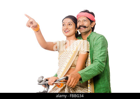 2 indian Rural farmer Married Couple Riding Bicycle finger pointing showing Stock Photo