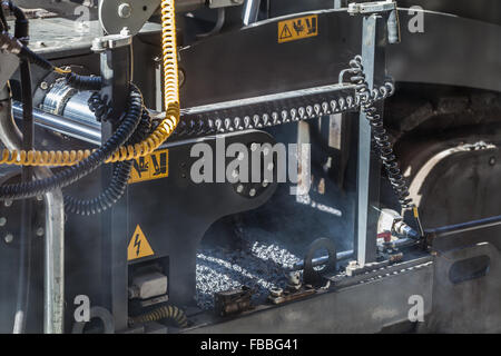 Urban road is under construction. Fragment of working paver machine Stock Photo