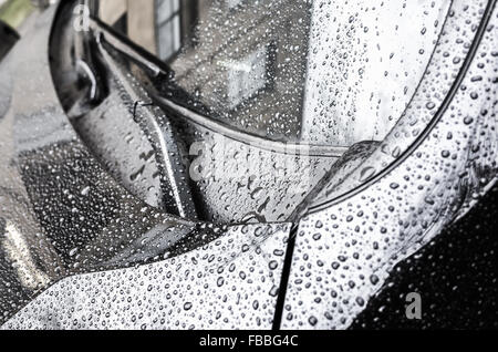 Black metallic shining car hood fragment and windshield wipers with raindrops on it, closeup photo with selective focus and shal Stock Photo