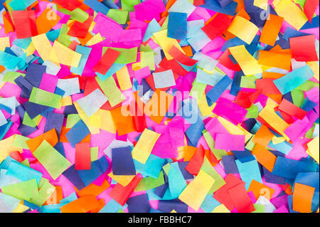 Brightly colored paper confetti background featuring red, yellow, blue, green, orange, and bright pink carnival colors Stock Photo