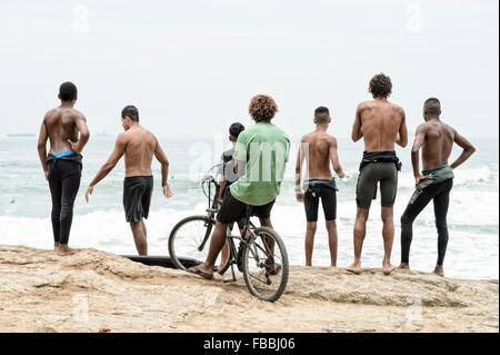 RIO DE JANEIRO, BRAZIL - OCTOBER 22, 2015: Brazilian surfers in wetsuits stand looking at incoming surf waves at Arpoador.
