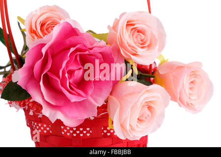 Pink fabric roses in wicker basket isolated on white background. Stock Photo
