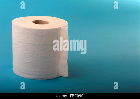 Single roll of toilet tissue on a blue background. Stock Photo