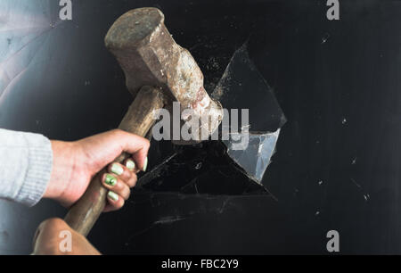 Closeup large metal hammer smashing black computer screen Stock Photo