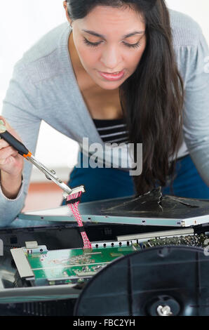 Hands working with electronic circuit board from broken computer screen using small screwdriver Stock Photo