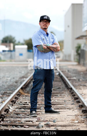 Young hispanic man with beard and tattoos drinking a cup of coffee ...