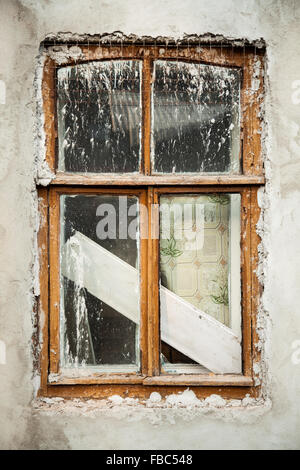 Background of rundown white stucco wall with wooden window covered in whitewash after renovation, parts of architecture, close-u Stock Photo