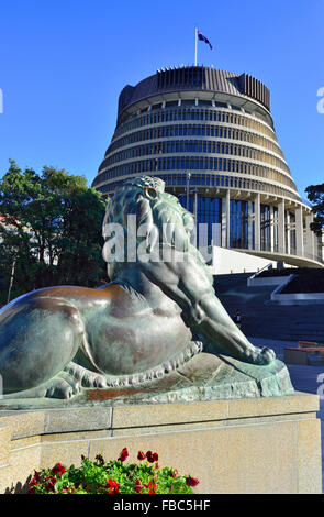 One of the two bronze lions on  Wellington's cenotaph with Parliament (The Beehive) behind , Parliament Grounds, Wellington, New Zealand Stock Photo