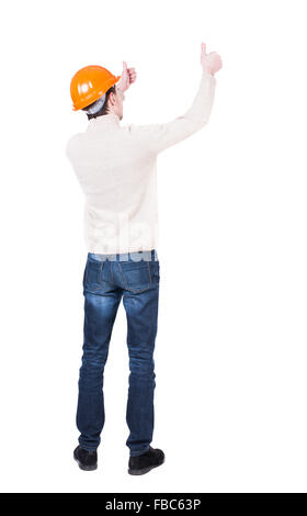 Back view of builder in helmet shows thumbs up. Rear view people collection. backside view of person. Isolated over white background. Engineer approval shows the fingers of both hands Stock Photo