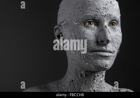 Statuesque woman in clay. Woman covered in clay. Spa treatment or Halloween mask? Stock Photo