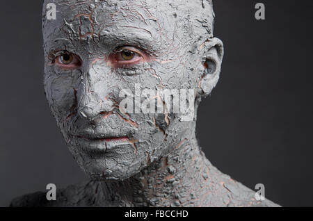 Statuesque woman in clay. Woman covered in clay. Spa treatment or Halloween mask? Stock Photo