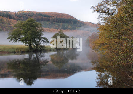 Early morning autumn mist and tree reflections in the river Dee by the Horseshoe Falls in Llangollen Wales