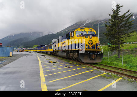 Alaska Railroad ARR diesel locomotive 4232, EMD SD70MAC, and passenger coaches in yellow and blue ARR livery. Seward, Alaska. Stock Photo