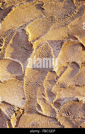 A texture background from wet sand and shadows due to low sunlight Stock Photo