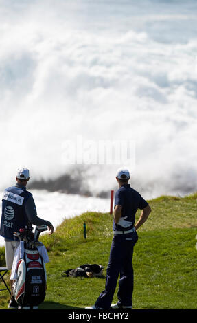 February 14, 2010; Pebble Beach, CA, USA;  Dustin Johnson and his caddy Bobby Brown watch large waves crash behind the seventh Stock Photo