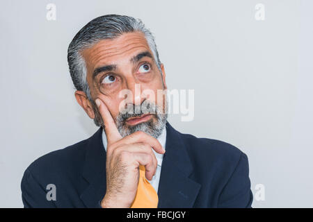 Adult man, mature, in suits. Bearded, grizzled, he thinks, deep in thought. Facial expressions, making faces. Stock Photo