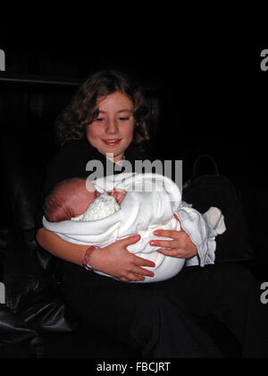 Young girl holding her infant cousin at her christening in Ireland Stock Photo