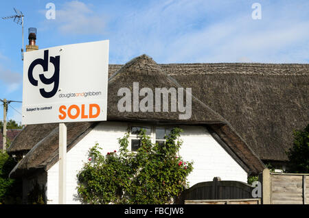 An estate agents sign outside a thatched cottage in Uffington, Oxfordshire, England, UK.