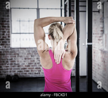 Composite image of rear view of muscular woman stretching her arm Stock Photo