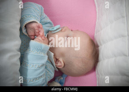 Sleeping four month baby boy lying in cot. Overhead view Stock Photo