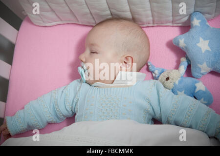 Sleeping four month baby boy lying in cot. Overhead view Stock Photo