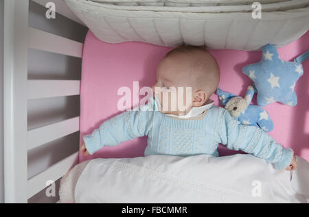 Sleeping four month baby boy lying in cot. Overhead view Stock Photo