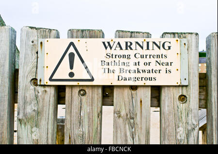 A warning sign on a wooden fence at a beach in Scotland Stock Photo