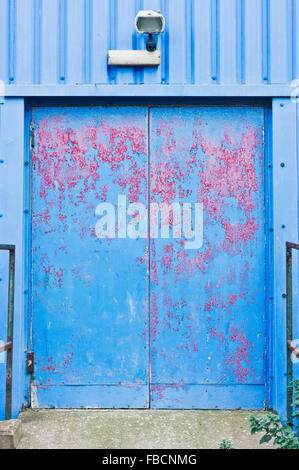 A blue metal door with peeling paint in a warehouse Stock Photo