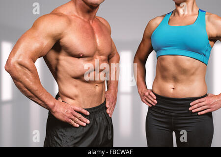 Composite image of midsection of muscular man and woman with hands on hip Stock Photo