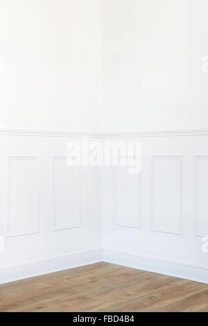 Empty white room corner with parquet floor and wood trimmed wall Stock Photo