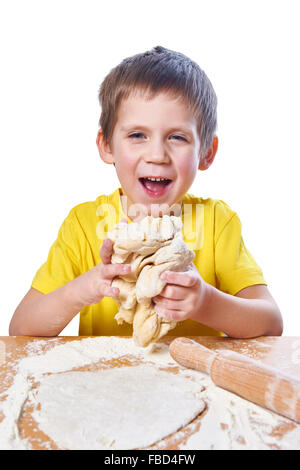 Happy boy kneads dough for pie on kitchen table isolated Stock Photo