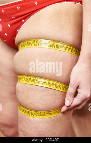 Fat woman measuring her thigh leg tape measure Stock Photo