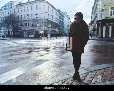 Young Woman Standing On Wet Street In City