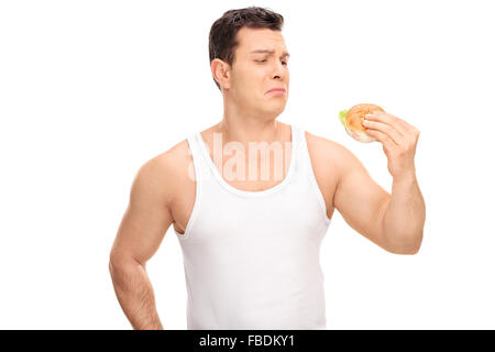 Studio shot of a sad young guy holding a small sandwich isolated on white background Stock Photo