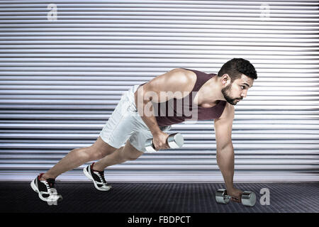 Composite image of muscular man doing push ups with dumbbells Stock Photo