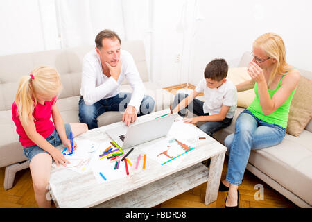 Kids drawing with happy parents on the couch Stock Photo