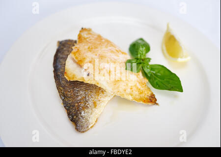 Baked fish fillets on white plate studio shot Stock Photo