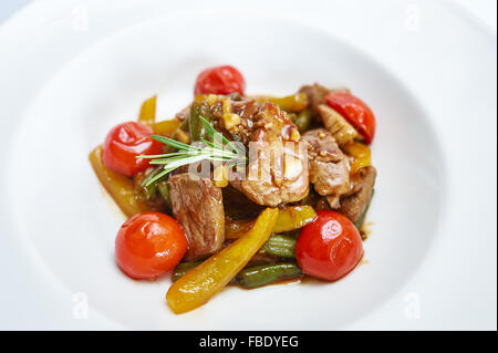 Pork with vegetables tomatoes on white plate Stock Photo