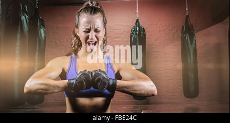 Composite image of aggressive female boxer flexing muscles Stock Photo