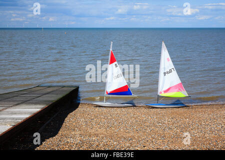 A pair of unoccupied windsurfing boards, standing at the water's edge at Herne Bay in Kent, next to a wooden slipway with a view Stock Photo