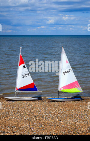 Unoccupied dinghies at water's edge in Herne Bay, Kent, England, on a summer's afternoon with blue sky and sea, soft clouds. Stock Photo