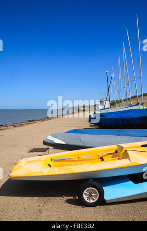 A row of dinghies outside a sailing club at Herne Bay, Kent, England on a warm, summer's day with blue sky and sea. Stock Photo