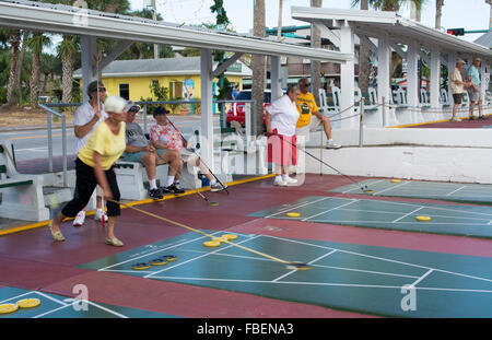 New Smyrna Beach Florida senior retired couples playing shuffleboard in game competition in town on Flagler Street Stock Photo
