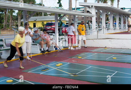 New Smyrna Beach Florida senior retired couples playing shuffleboard in game competition in town on Flagler Street Stock Photo