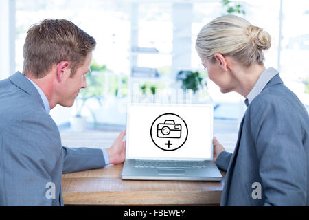 Composite image of business people looking at blank screen of laptop Stock Photo